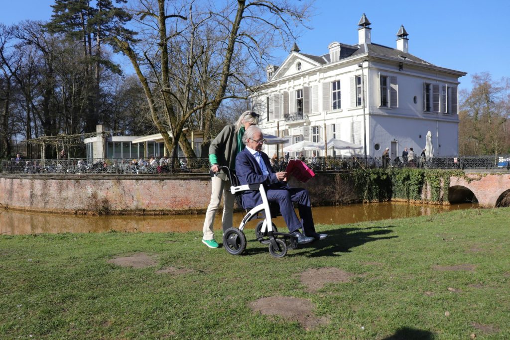 Man in wheelchair with assistance near a building